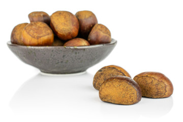 Lot of whole sweet brown chestnut in dark ceramic bowl isolated on white background