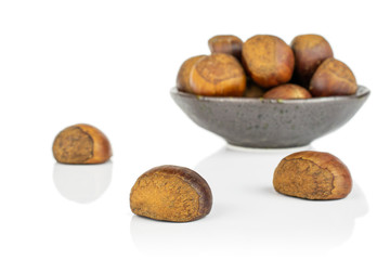 Lot of whole sweet brown chestnut in dark ceramic bowl isolated on white background