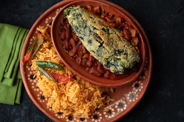Chille relleno and Mexican rice served in traditional clay plate