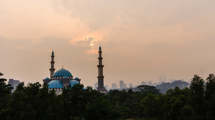 Fototapeta na wymiar Sunrise over silhouette mosque and hazy
