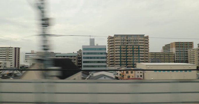 High speed train ride in Japan slowing down arriving at Kyoto, view of the city from the train window