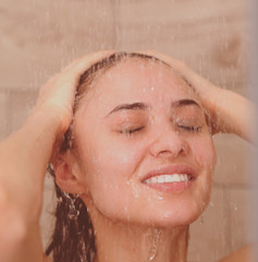 Young beautyful woman under shower in bathroom.