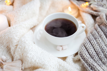 Obraz na płótnie Canvas Warm knitted blanket, cup of coffee, marshmallows, Christmas lights, vintage toy, candles