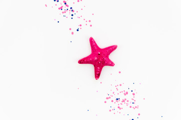 Flat lay summer vacation concept with purple starfish and confetti on white background, flat lay copy space
