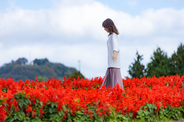 女性　花畑を歩く　赤　コピースペース 