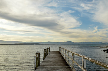 Fototapeta premium Old timber pier leading to lake with cloudy sky