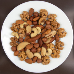 Different kinds of nuts on a white plate. Healthy and protein food.