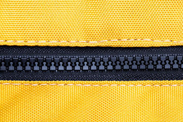Black plastic zipper fashion background. Yellow fabric backpack texture.
