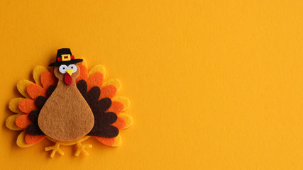orange brown and yellow crafted felt turkey laying flat on an orange background with copy space	 - Powered by Adobe