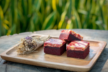 Red velvet cream cheese brownies on wooden plate