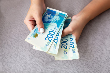 Close up of a girl counting Israeli money. Counting 200 Israeli shekel bills - close up on large...