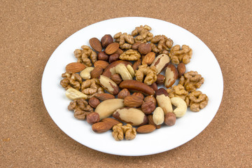 Different kinds of nuts on a white plate. Healthy and protein food.