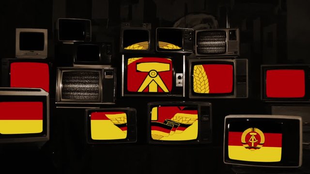  Flag of the German Democratic Republic (East Germany) and Retro TVs. Iron Curtain and Berlin Wall Concept. Sepia Tone. 