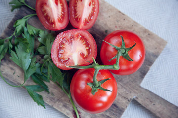 Bright red, ripe organic tomatoes on the vine laying on a chopping board on a kitchen counter top