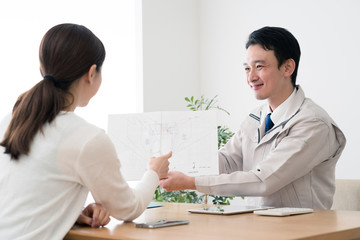 顧客に設計プランを見せるビジネスマン