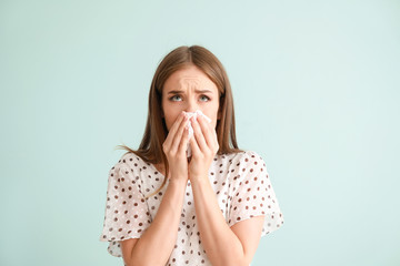 Young woman suffering from allergy on light background - obrazy, fototapety, plakaty