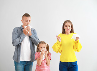 Young family suffering from allergy on light background