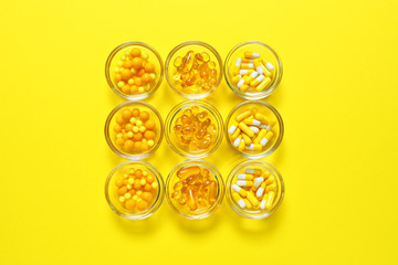 Bowls with different pills on color background