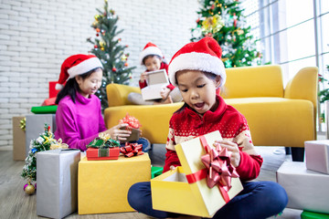 Obraz na płótnie Canvas Cute asian child girls surprise with gift and helping to decorate together for celebrate in Christmas festival