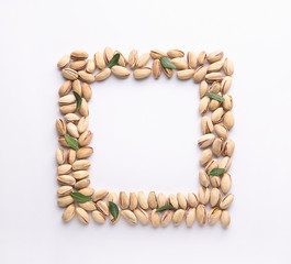 Frame made of tasty pistachio nuts on white background