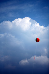 a colorful balloon floating in the air in the blue sky and white clouds