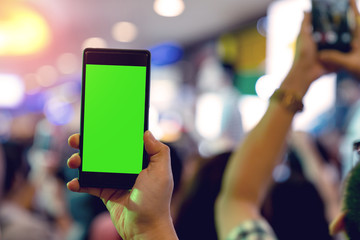 Hands holding mobile smartphone with light bokeh in mini concert blur background