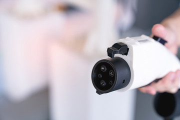 hand holding plug for charging battery of an electric car