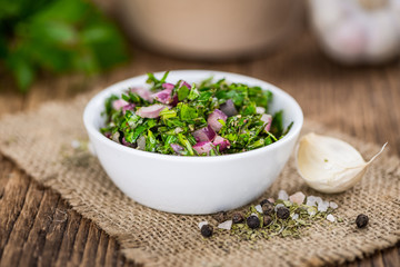 Wooden table with Chimichurri (detailed close-up shot; selective focus)
