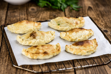 Some Empanadas on a vintage wooden table (selective focus; close-up shot)