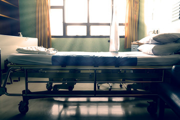 Empty  hospital bed with sunlight from the window,vintage tone