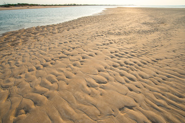 The abstract and texture of sand beach with golden light during sunrise/sunset.