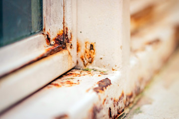 Close up of rust on an old white iron window in the corner of the frame with a blurred background