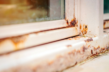 Close up of rust on an old white iron window in the corner of the frame with a blurred background