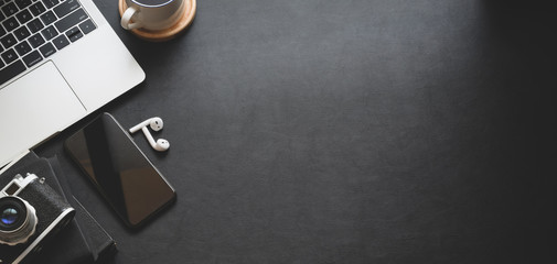 Dark modern workspace with laptop computer, smartphone and office supplies