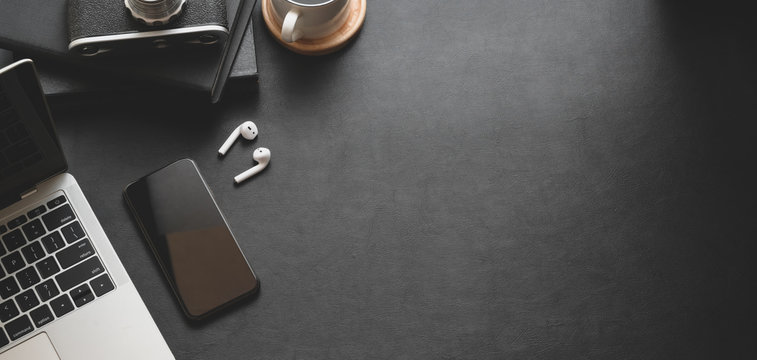 Top view of dark modern workplace with laptop computer and office supplies