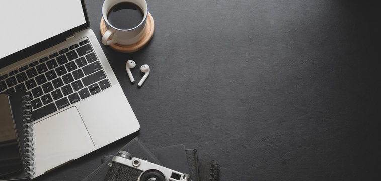 Close-up view of dark modern workplace with laptop computer and office supplies