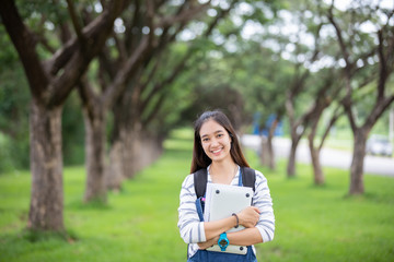Fototapeta premium beautiful Asian girl student holding books and smiling at camera and learning and education concept on park in summer for relax time