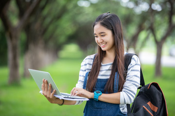 Fototapeta premium beautiful Asian girl student holding books and smiling at camera and learning and education concept on park in summer for relax time