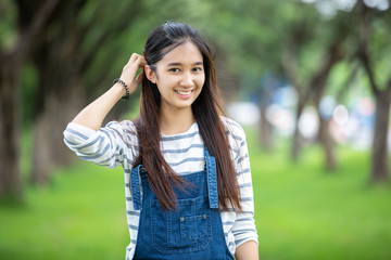 Smiling beautiful Asian girl at tree on park in summer for relax time