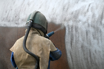 engineer sandblasting a steel casing