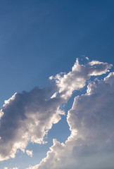 Dramatic clouds rimmed with sunlight, blue sky background