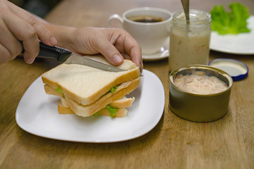 female cutting a sandwich for breakfast with tuna mayonnaise