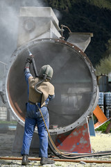 engineer sandblasting a steel casing
