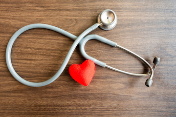 Red heart with stethoscope on wooden background. Copy space.