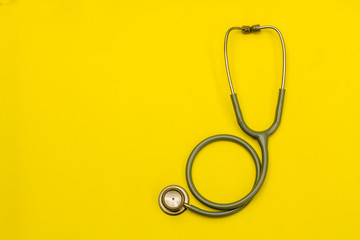 Stethoscope on a yellow background with space for text.