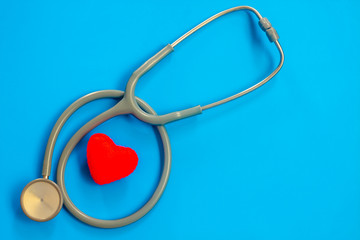 Stethoscope and red heart on a blue background with space for text.