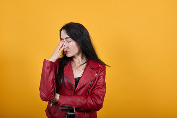 Portrait of tired exhausted young woman in vivid casual clothes keeping eyes closed, putting hand on nose isolated on bright blue background in studio. People lifestyle concept.