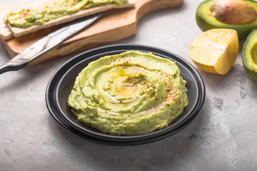 Green hummus. or  humus, delicious cream of chickpeas and avocado on a wood background.