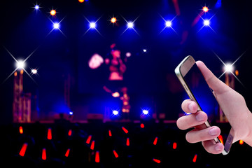 Hands holding mobile smartphone with light bokeh in concert blur background