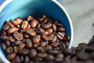 coffee beans in the white cup on the beige background close-up